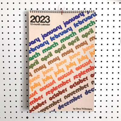 Front cover of calendar with each month written in repeated rainbow text
